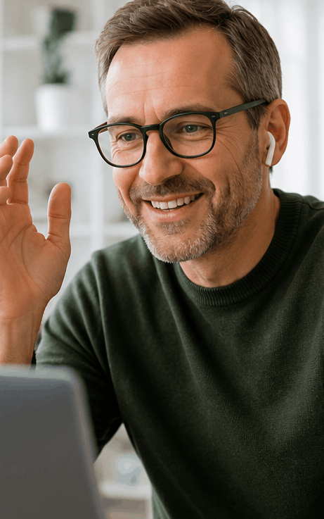 Smiling man with glasses and a green sweater gesturing during a video call